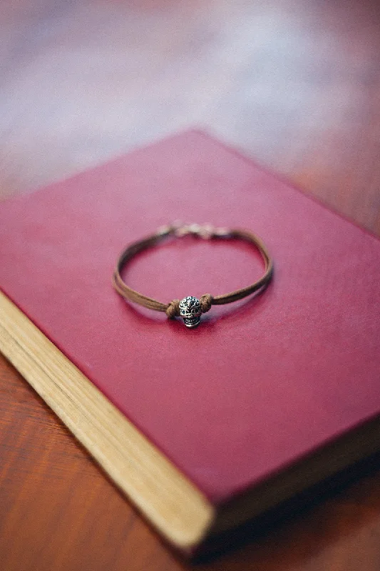 Men's bracelet with a silver skull bead charm and a brown cords